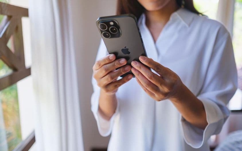 A woman using an iPhone 15 Pro Max at home.