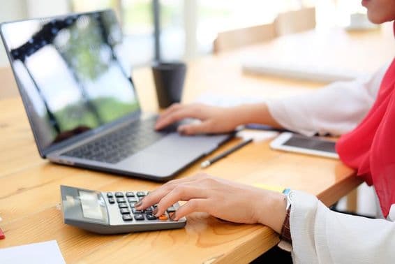 Female worker in Dubai calculating financial data with a calculator.