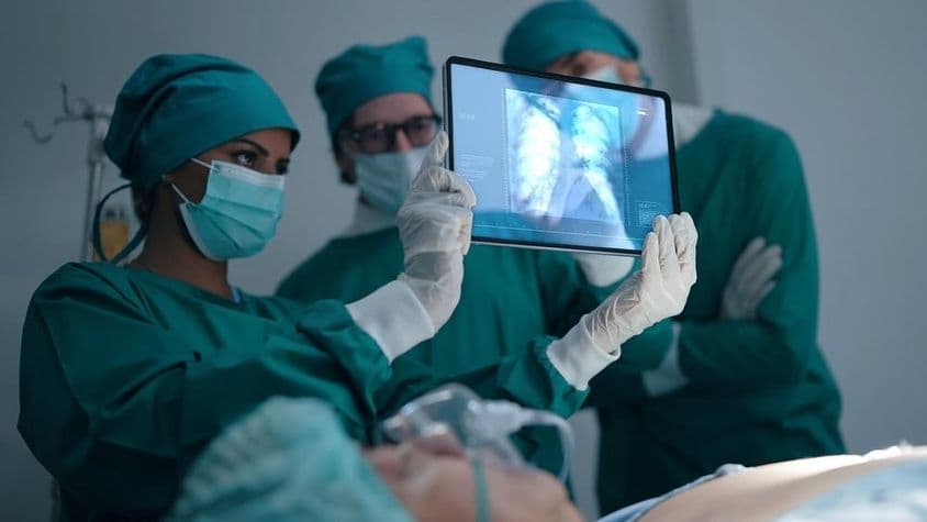 Professional medical team discussing and reviewing an X-ray of a patient with pneumonia.