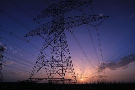 High voltage towers under sunset with a view of Dubai cityscape.