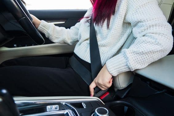 Female driver buckling her seatbelt.