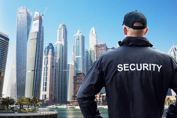 Male security guard standing and watching the cityscape from behind.