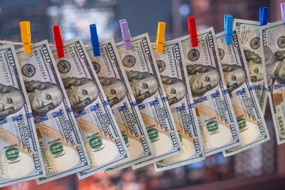 A 100 US dollar bill hanging on a clothesline with wooden clips.