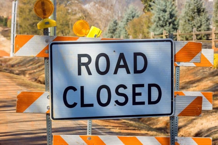 Orange striped road closure sign.