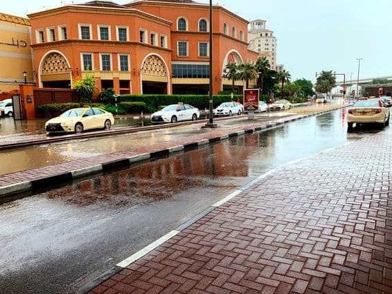 Cars driving through flooded Dubai streets in the rain.
