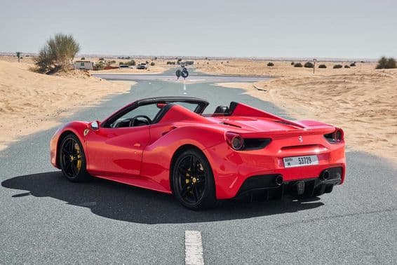 Red Ferrari 488 on an abandoned Dubai desert road.