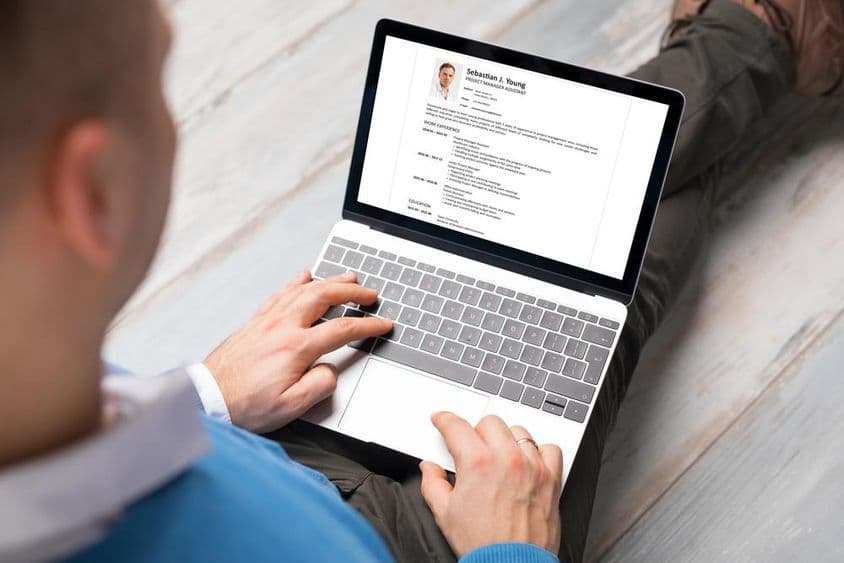 A person writing their resume on a laptop.