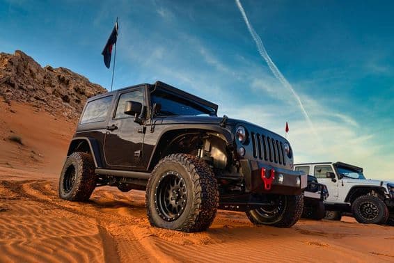 Jeep Wrangler off-road adventure on a sand dune in Dubai's red desert.