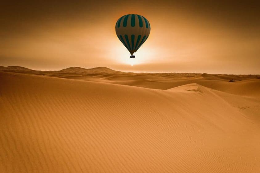 Desert and hot air balloon landscape at sunrise.