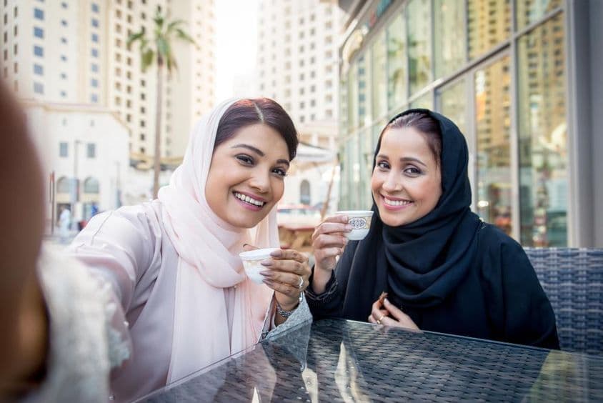 Arab women enjoying coffee outdoors in Dubai.