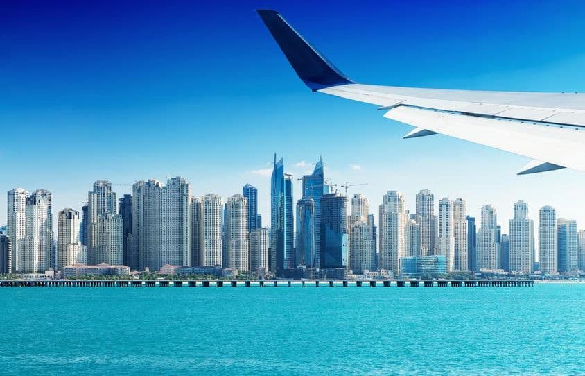 Airplane flying over Dubai skyscrapers.