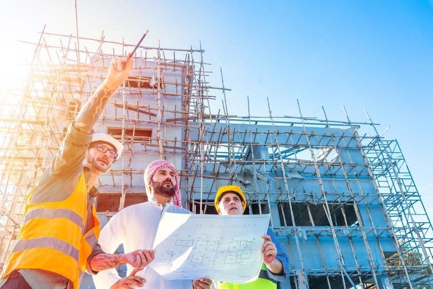 Engineering team inspects building blueprints at a construction site.