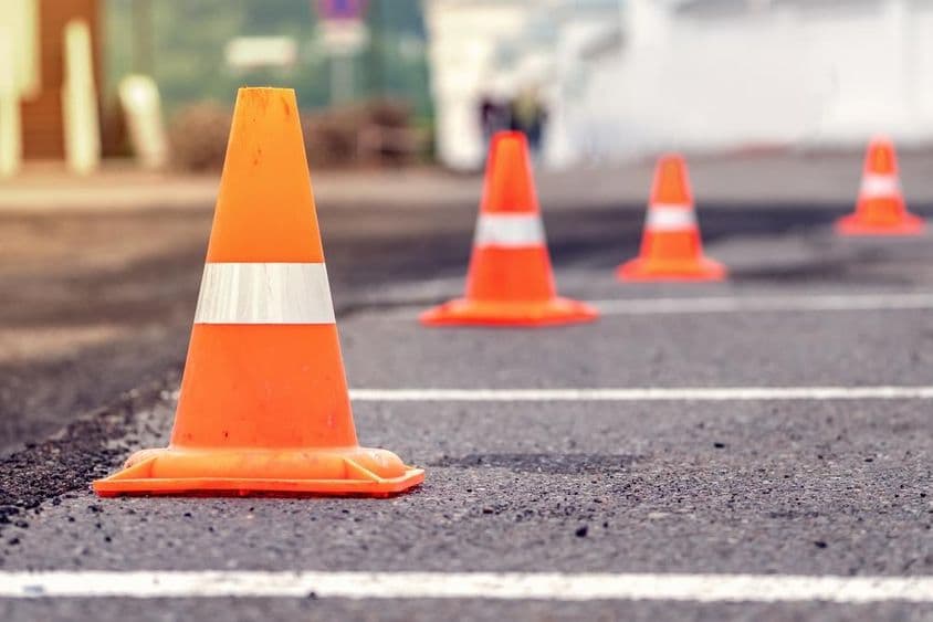 Rows of bright orange traffic cones on an asphalt road.