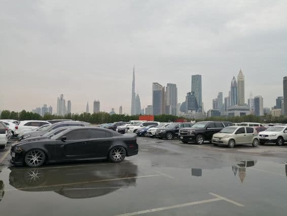Rain aftermath in a parking area near the Dubai World Trade Center and Burj Khalifa.