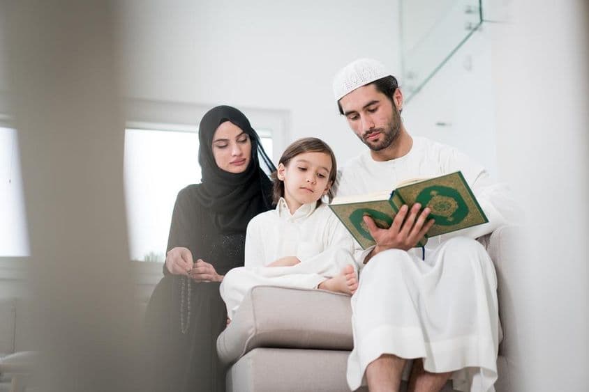 Young parents and a little boy reading from a book.