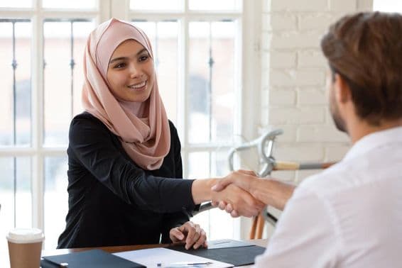 Arab female HR manager in hijab shaking hands with a male job applicant.