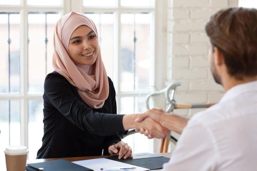 Arab female HR manager in hijab shaking hands with a male job applicant.