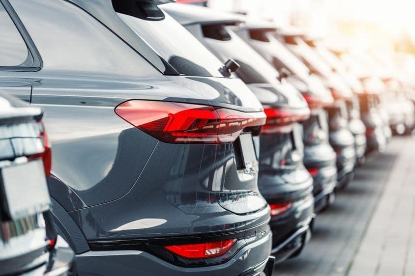 Rear view of a fleet of modern new SUV cars at a dealership parking lot.