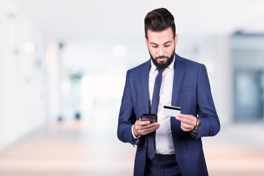 Arab businessman holding a smartphone and credit card.