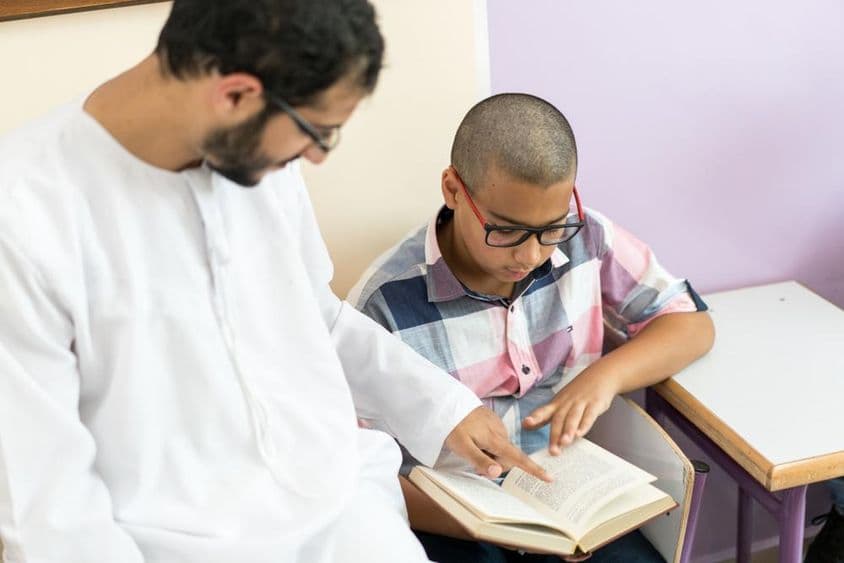 Young Arab teacher studying with a schoolboy.