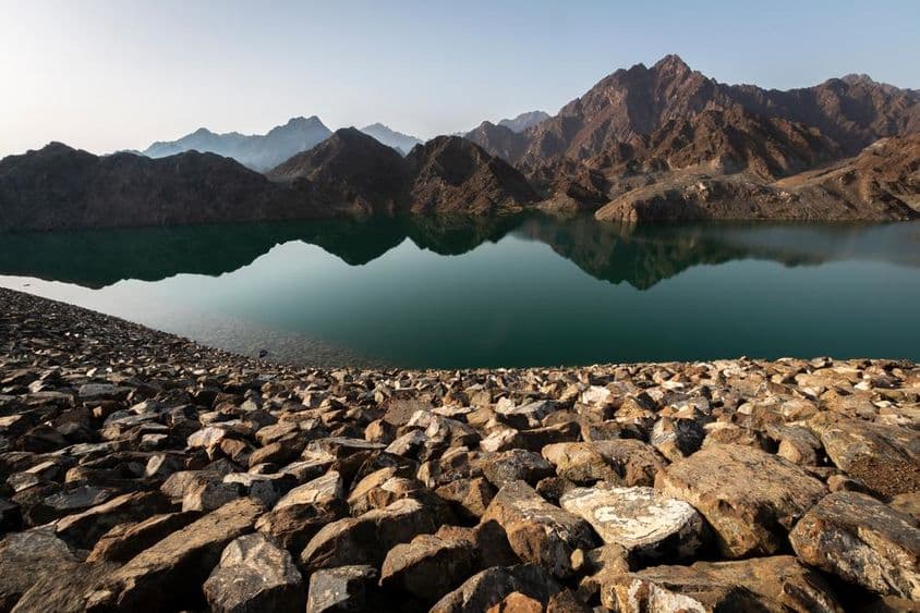 Hatta dam and mountains, stunning view reflecting rocks and mountains at sunrise.