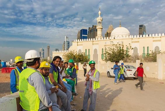 Construction workers taking a break next to a mosque in modern downtown Dubai.
