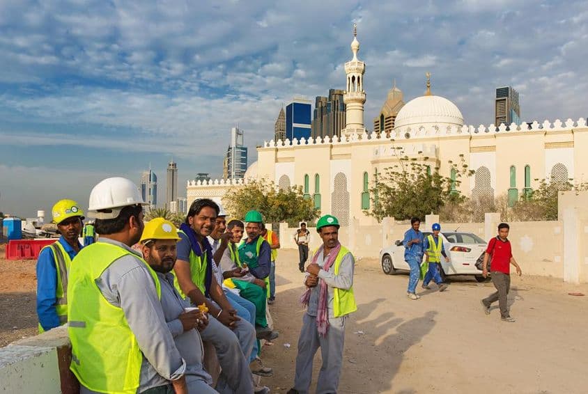 Construction workers taking a break next to a mosque in modern downtown Dubai.