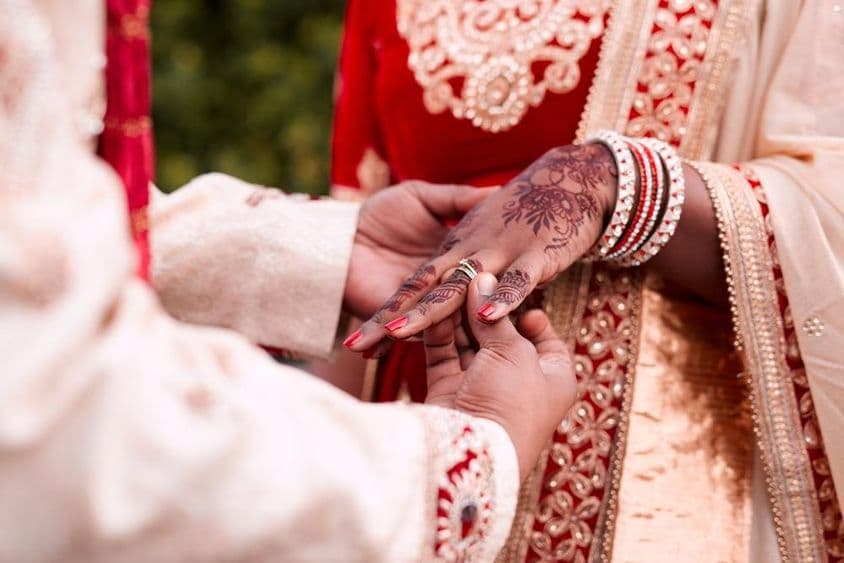 An Indian bride's hand receiving a ring.