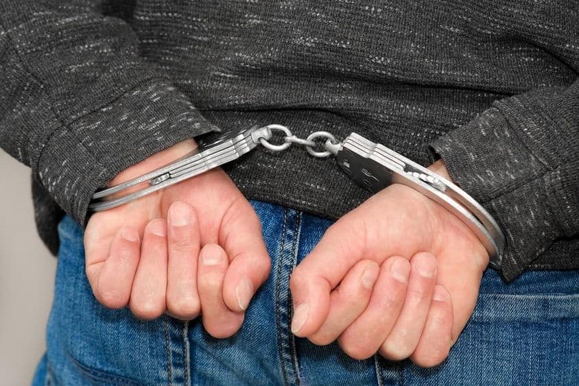 A criminal in handcuffs apprehended for crimes.