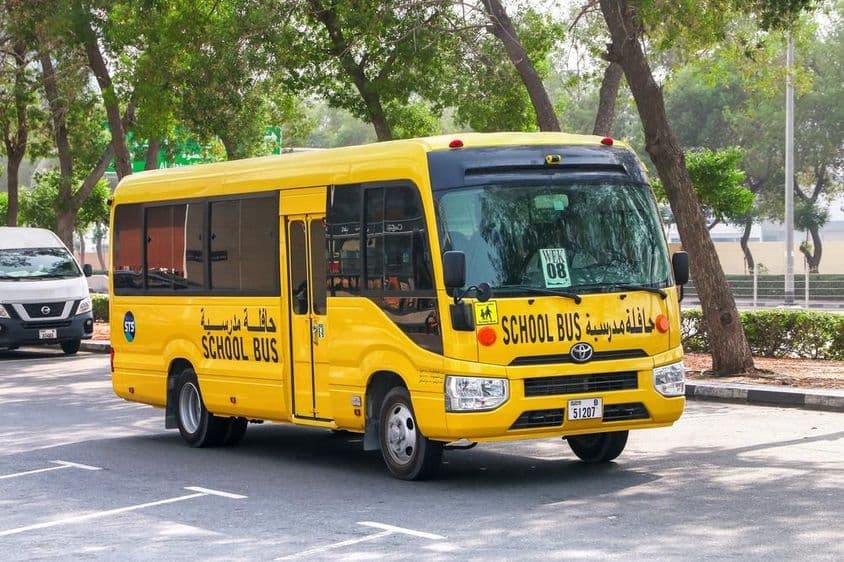 Toyota Coaster school bus on a Dubai city street.
