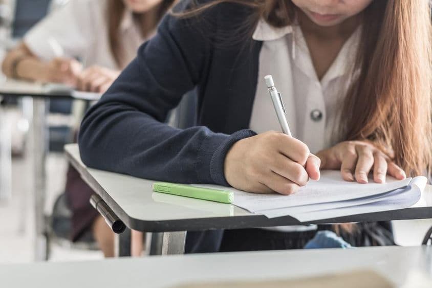 School student writing an exam in classroom.
