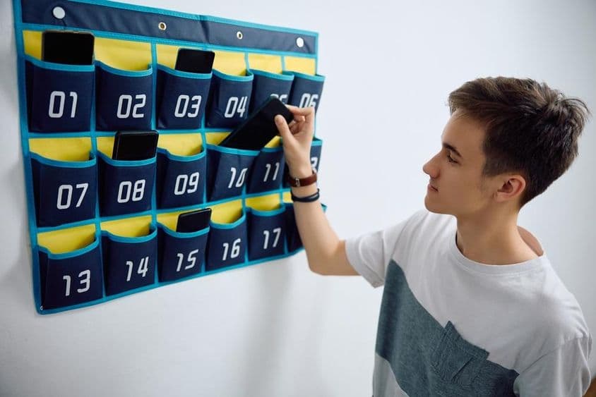 Student leaves smartphone in a wall-mounted phone organizer.