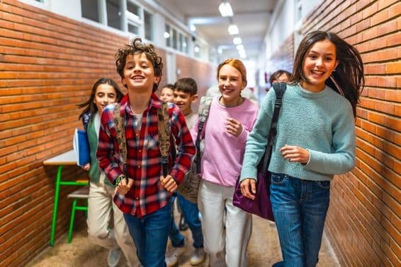 Cheerful students running through the school hallway.