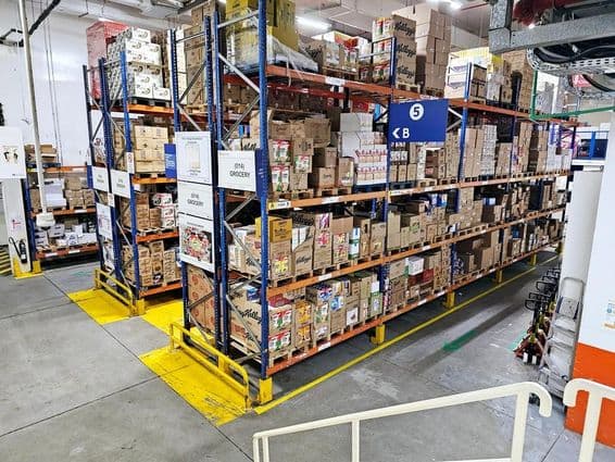 Warehouse with shelving systems, labeled product categories, and safety markings aiding smooth operations.