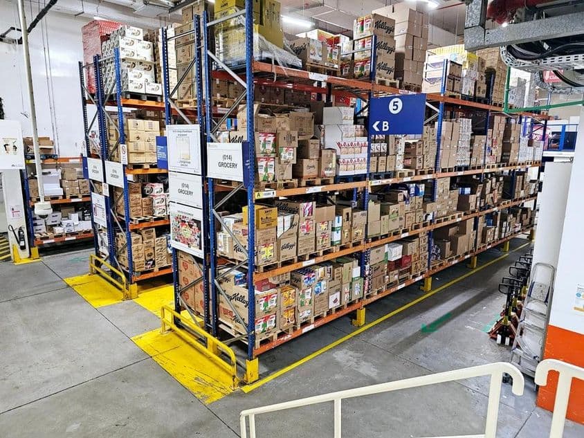 Warehouse with shelving systems, labeled product categories, and safety markings aiding smooth operations.
