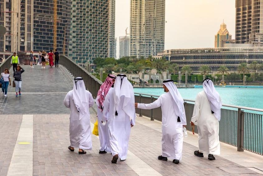 Arab men in traditional white attire walking in downtown Dubai.