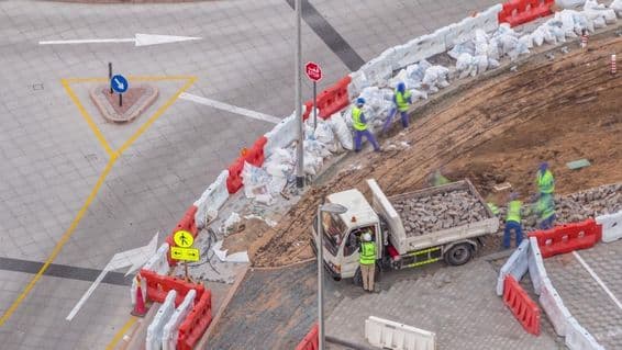 Sidewalk repair process with many construction workers and equipment breaking sidewalk and concrete.