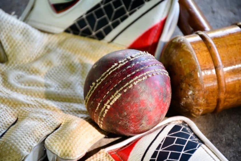 Cricket equipment, ball, glove, and bat.