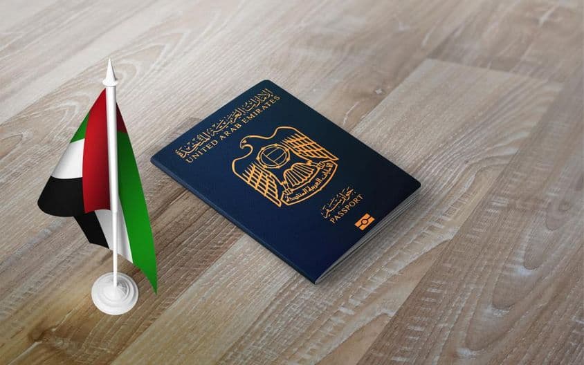 United Arab Emirates passport on a wooden surface, with a national flag.