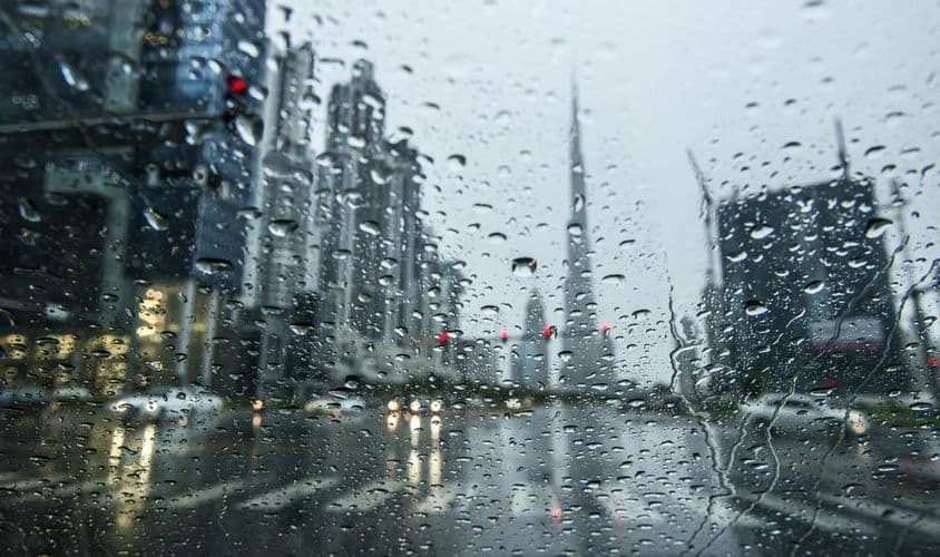 Rain in Dubai, cityscape blurred in view.