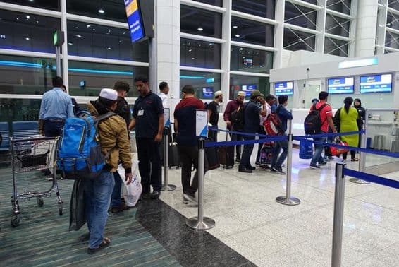 People standing in line for boarding at Dubai International Airport gate.