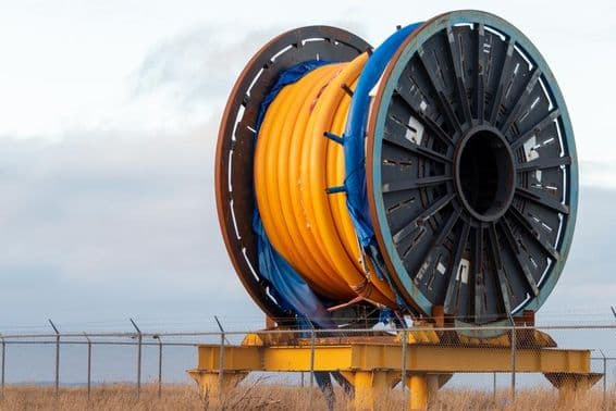 Massive underwater industrial fiber optic cable on a metal spool on a ship deck.