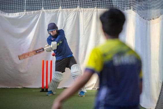 Members of a cricket club in indoor winter net practice.