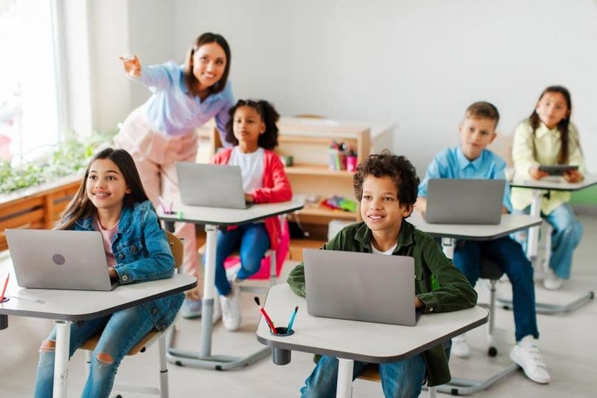 Group of children receiving a lesson using laptops.