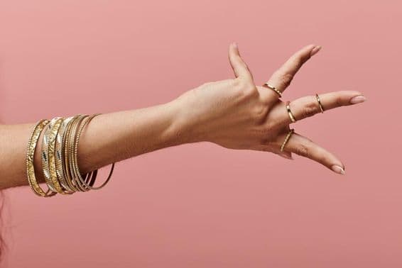 Indian woman elegantly posing with gold bangles on her wrist.