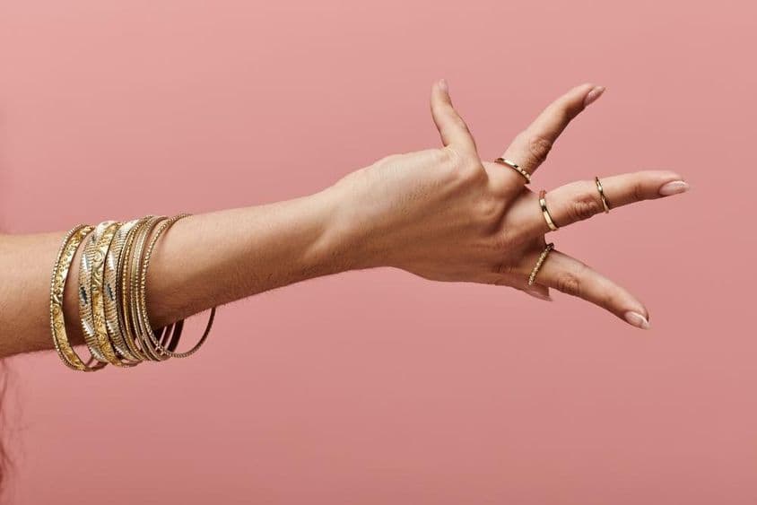 Indian woman elegantly posing with gold bangles on her wrist.