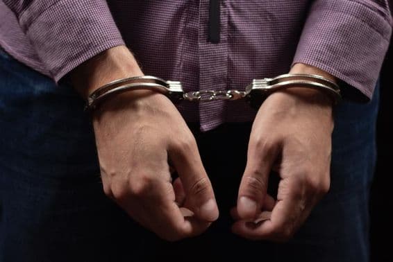 Thief arrested in handcuffs for burglary and fraud.