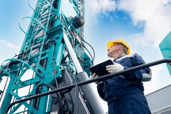 Industry operator using a digital tablet to control a drilling platform.
