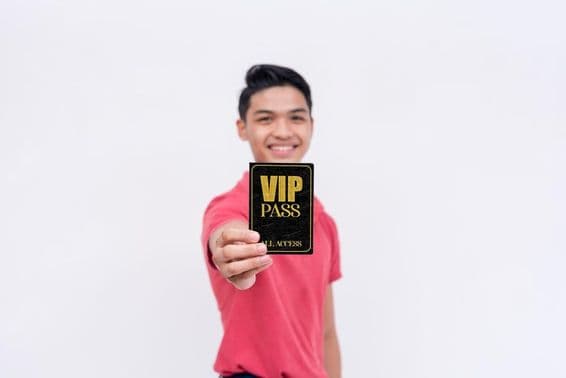 A happy man holding a VIP ticket or badge.