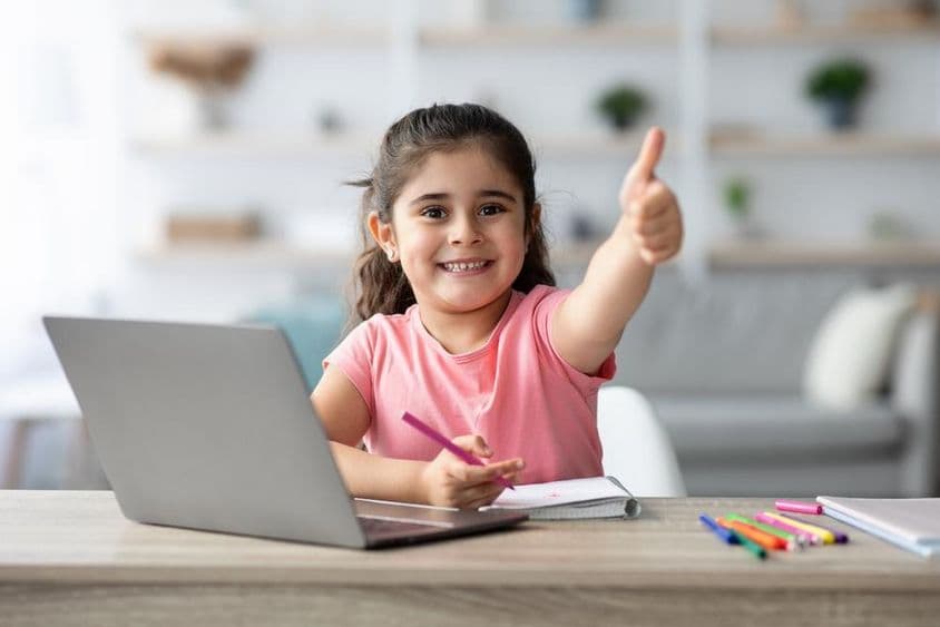 Arab girl learning at home with a laptop, giving thumbs up.